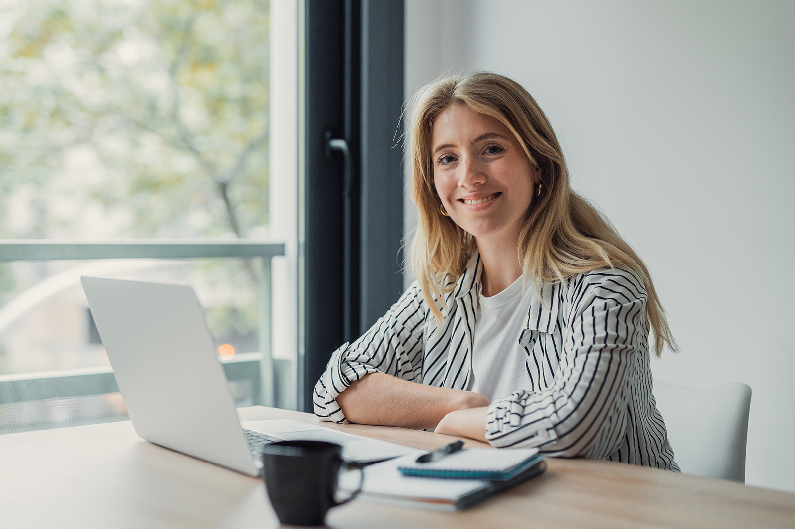 Kvinne arbeider på laptop ved et lyst kontor – illustrasjon til gratis KI-kurs i Microsoft Copilot.