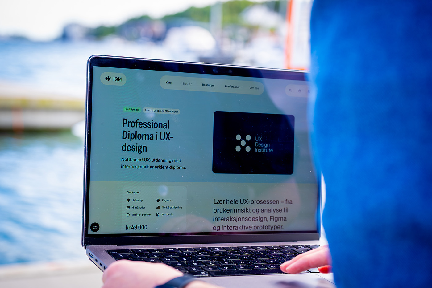 Person bruker laptop med informasjon om Professional Diploma i UX-design fra IGM og UX Design Institute.